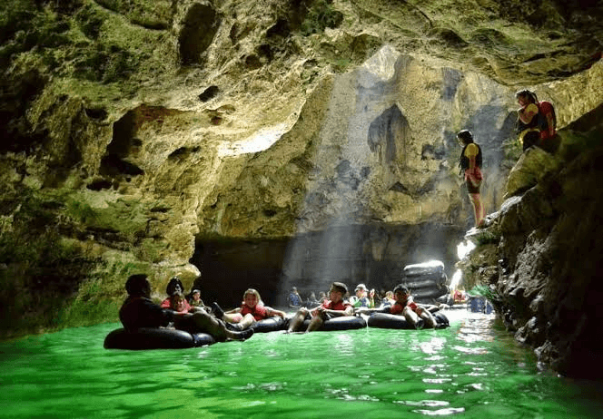 Guests tubing in a green cave river