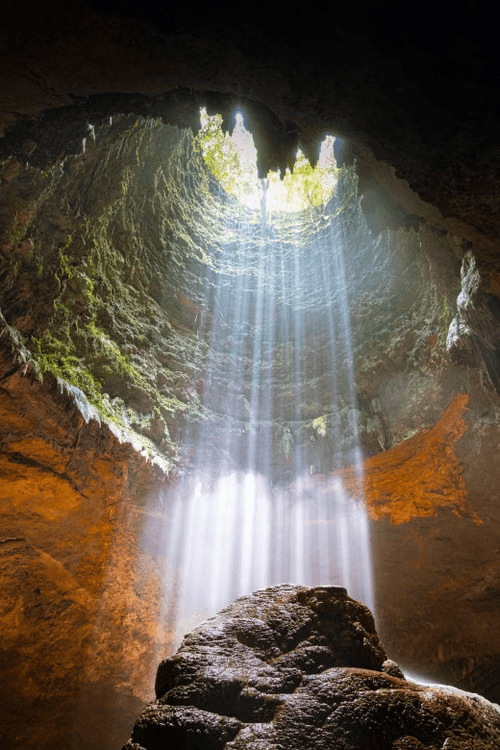 Sunbeams falling into the Jomblang Cave shaft