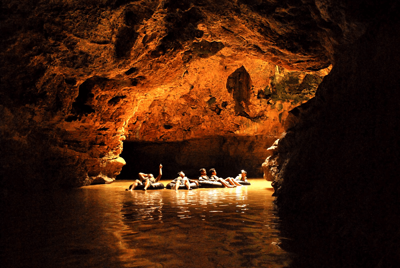 Guests cave tubing in a warm-lit cave