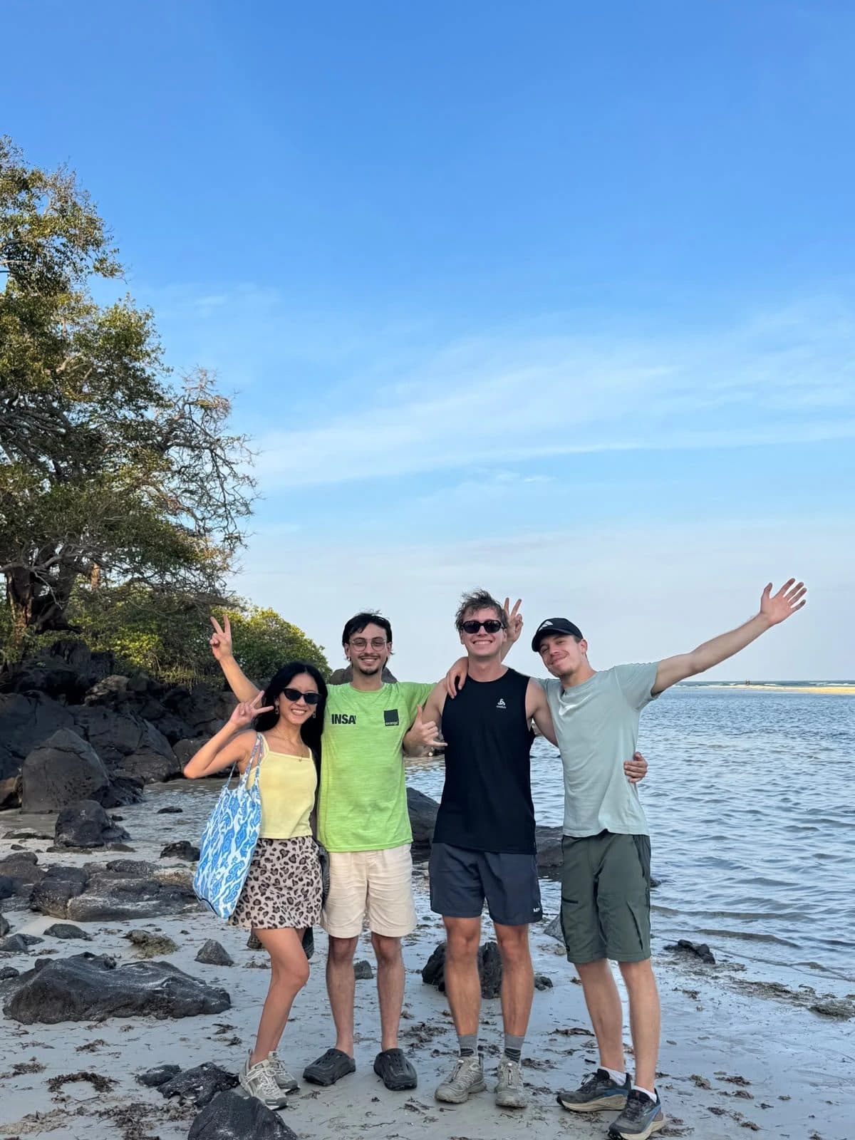 Guests on Bama beach with black rocks and mangroves