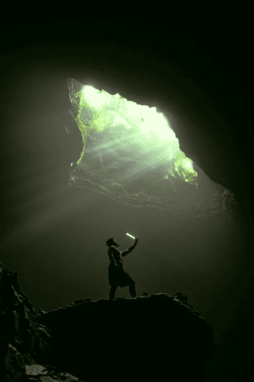 A visitor with a light under the cave opening